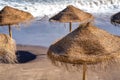 Straw beach umbrellas along a beautiful shoreline at dusk