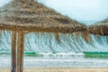 Straw Beach Umbrellas on Sand Beach Turquoise Sea Waves Blue Sky Background. Bright Sunlight. Summer Vacation Wanderlust Traveling Royalty Free Stock Photo