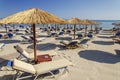 Straw beach umbrellas and sun chairs on a sandy beach on the east coast of Zakynthos island, Greece Royalty Free Stock Photo