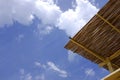 Straw cover the roof of a seaside terrace or veranda. Beautiful sky and clouds background.