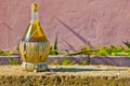 STRAW-COVERED WINE FLASK on tufa stone block, set against a rust Royalty Free Stock Photo