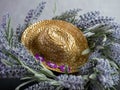 Straw cowgirl or cowboy hat decorated with purple felt flowers on top of a lavender flower wreath with a black and plaster