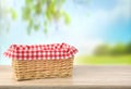 Straw empty basket decorated with picnic checkered cloth nature background