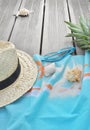 Beach towel with sunglasses and pineapple on wooden terrace