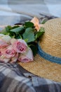 Straw hat and a bouquet of pink roses on a plaid Royalty Free Stock Photo