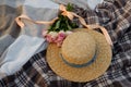 Straw hat and a bouquet of pink roses on a plaid Royalty Free Stock Photo