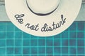 Straw hat with Do not disturb wording at the pool edge