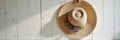 Straw hat with floral decoration hanging on white wooden wall Royalty Free Stock Photo