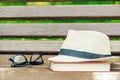 straw hat, glasses and a thick book on a wooden bench Royalty Free Stock Photo