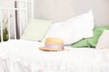 Straw hat is lying on the white bedding on the bed. Summer weekend concept. Leisure, weekend, trip. Woman accessories from above.