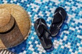 Straw hat and rubber flip flops by the pool macro photo Royalty Free Stock Photo