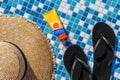 Straw hat rubber flip flops sunscreen for body and face by the pool Royalty Free Stock Photo