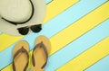 Straw hat, sun glasses, flip flops on yellow and light green woo