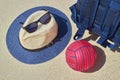 Straw hat, sun goggles, blue backpack and red water polo ball