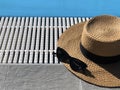 Straw hat and sunglasses along the poolside. Copy space. Summer concept. Sun protection. Beach style. Top view Royalty Free Stock Photo