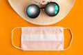 Straw hat, sunglasses and medical mask on oramge background, top view. Royalty Free Stock Photo