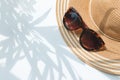 Straw hat and sunglasses with palm tree shadow