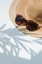 Straw hat and sunglasses with palm tree shadow