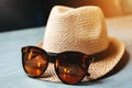 Straw hat with sunglasses on the table. Summer atmosphere.
