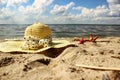 Straw hat and two red shells lie on the sand close up a background of the sea Royalty Free Stock Photo