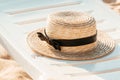 Straw hat on the white deck on the beach. Lounge chair next to a sea. Summer, vacation background.
