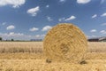 Straw roll bales with crop field, photovoltaic panel and blue sky in background