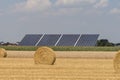 Straw roll bales with crop field, photovoltaic panel and blue sky in background Royalty Free Stock Photo