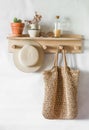 Straw shopping bag, hat on a wooden shelf in the hallway. Simple interior design