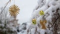 Straw star and angel hanging on a branch in the snow