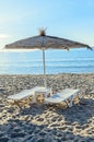 Straw sun umbrellas and white plastic sunbeds, beach with sand n
