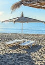 Straw sun umbrellas and white plastic sunbeds, beach with sand