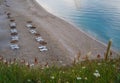 Straw sunshades and sunbeds on the empty sandy beach Royalty Free Stock Photo