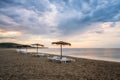 Straw sunshades and sunbeds on the empty sandy beach Royalty Free Stock Photo