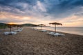 Straw sunshades and sunbeds on the empty sandy beach Royalty Free Stock Photo