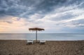 Straw sunshades and sunbeds on the empty sandy beach Royalty Free Stock Photo