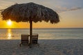 Straw umbrella at the beach on Aruba in the Caribbean Sea at sunset Royalty Free Stock Photo