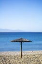 Straw umbrella on an empty sandy beach. Blue sea and sky background Royalty Free Stock Photo