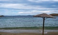 Straw umbrella on an empty sandy beach, cloudy sky background Royalty Free Stock Photo