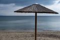 Straw umbrella on an empty sandy beach. Dark blue sea and sky background Royalty Free Stock Photo