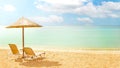 Straw umbrella and two sunbeds on a sunny golden beach seashore