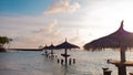 Straw umbrella in the water, sunset. Resort on a tropical island.