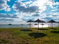 Straw umbrellas on green grass harsh shadow, sand beach vivid blue sea water sky background sunbeam. Scenic landscape