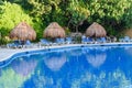 Straw umbrellas and lounge chairs around outdoor swimming pool. Riviera Maya, Cancun, Mexico Royalty Free Stock Photo