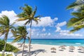 Straw umbrellas and palm trees on beautiful tropical beach. Green palm leaves in the wind on the background of the azure Caribbean Royalty Free Stock Photo