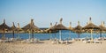 Straw umbrellas and sunbeds on the seafront. There is nobody on the beach. The first summer days at sea