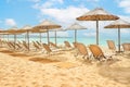 Straw umbrellas and sunbeds on a sunny golden tropical beach seashore Royalty Free Stock Photo