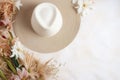 straw weaved hat with dry leaves and wild flowers. Bohemian background, boho flat lay composition Royalty Free Stock Photo