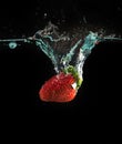 Strawberri splashing into water on the black
