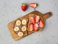 Toast with chocolate and fruits on a wooden board. Strawberries and bananas on stone kitchen table background. Top view Royalty Free Stock Photo