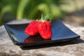 Strawberries on a black plate outdoors